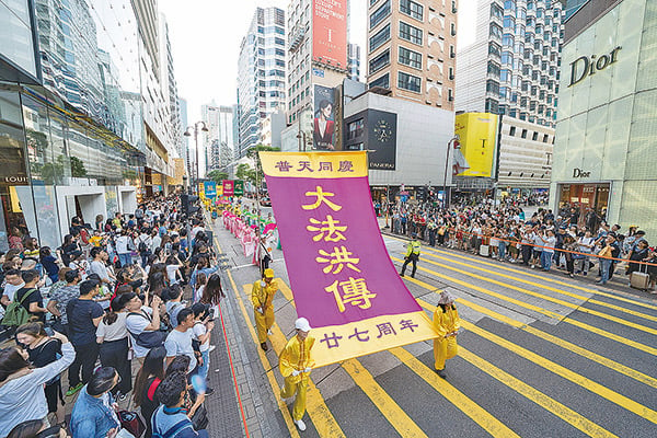 5月12日，香港法輪功學員舉行集會遊行慶祝世界法輪大法日。圖為遊行隊伍途經尖沙咀廣東道，大批遊客和市民夾道觀看，紛紛拍下盛大的遊行場面。（李逸／大紀元）