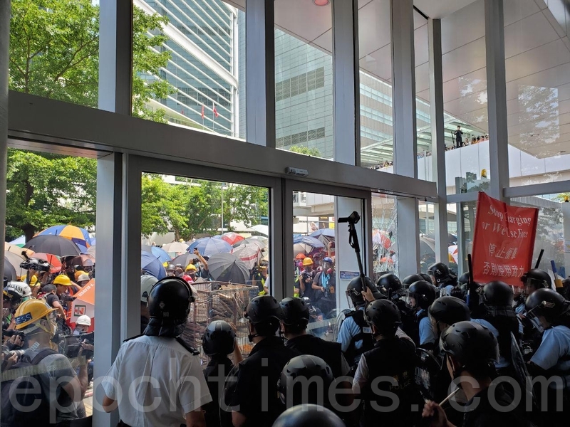 一批示威者群聚立法會門外抗議，有人朝大門丟擲物件，警方舉起紅旗警告。（孫青天／大紀元）