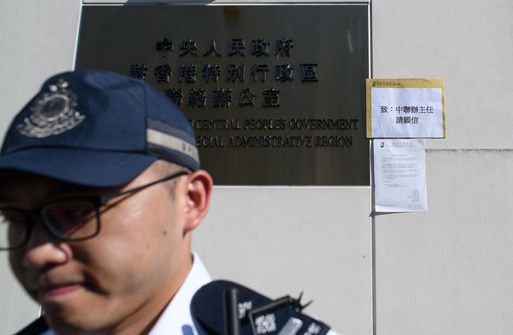 圖為一名警員守在香港中聯辦的辦公樓標牌下。（ANTHONY WALLACE/AFP/Getty Images）