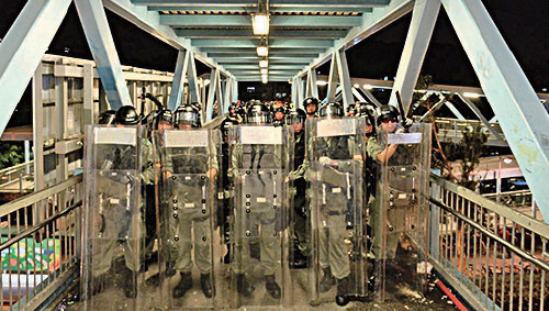 8月21日大批市民在西鐵元朗站內靜坐抗議，全副武裝防暴警在站外其中一座天橋佈防。（宋碧龍／大紀元）