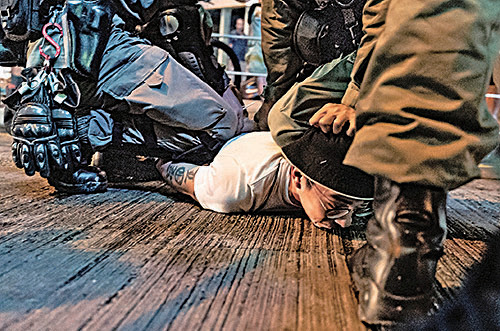 幾個月來，香港人不畏當局暴力鎮壓，堅持民主抗爭。圖為 10 月 13 日，一名抗議者被警察壓制在地。(Getty Images)