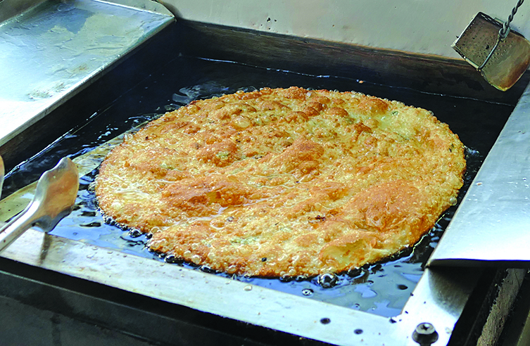 美味的低油蔥油餅，老闆自製無油麵團，擀成一個大圓餅，入鍋兩面煎香。