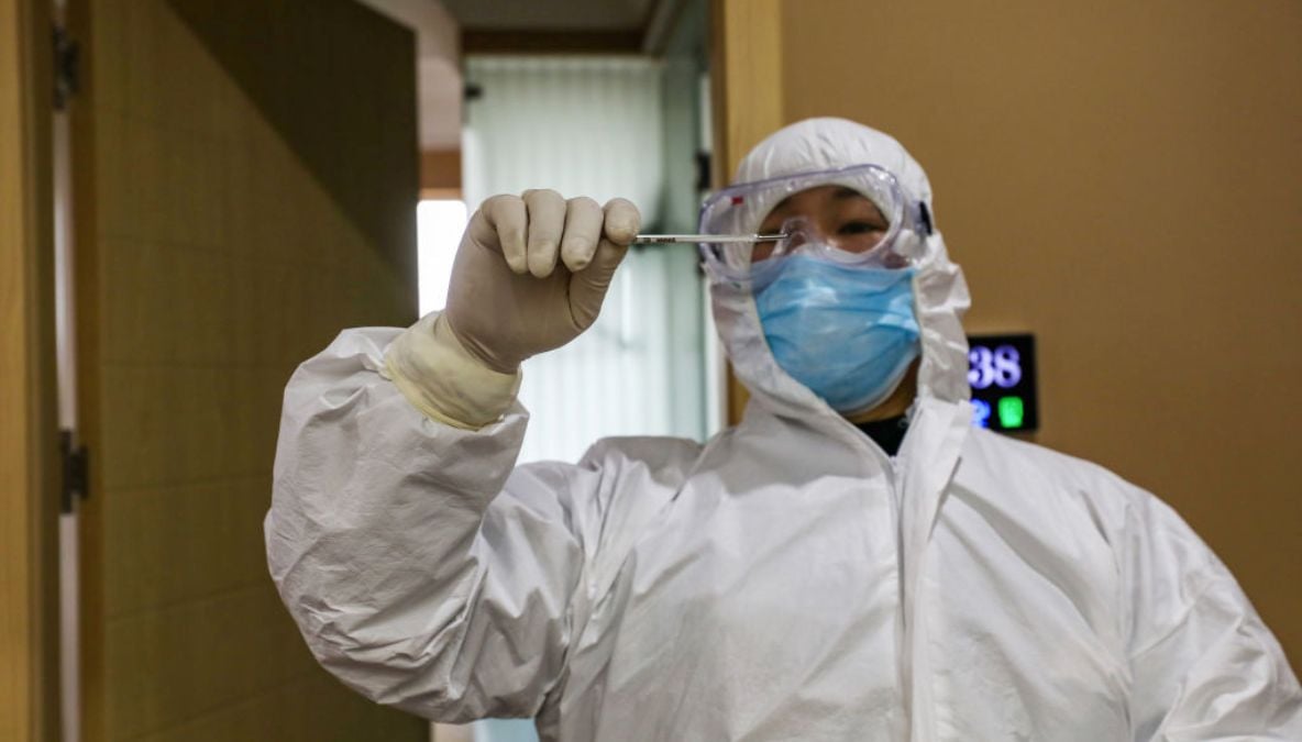 2020年2月3日中國湖北省武漢市的隔離區一名醫務人員在檢查溫度計讀數，該地區爆發了嚴重的新型冠狀病毒引起的肺炎疫情。(STR/AFP via Getty Images)