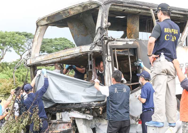 台灣國道2號往西3公里處19日中午12時57分，1輛行駛中陸客團遊覽車撞護欄起火，26人全部罹難。警消人員將遺體抬出。（中央社）