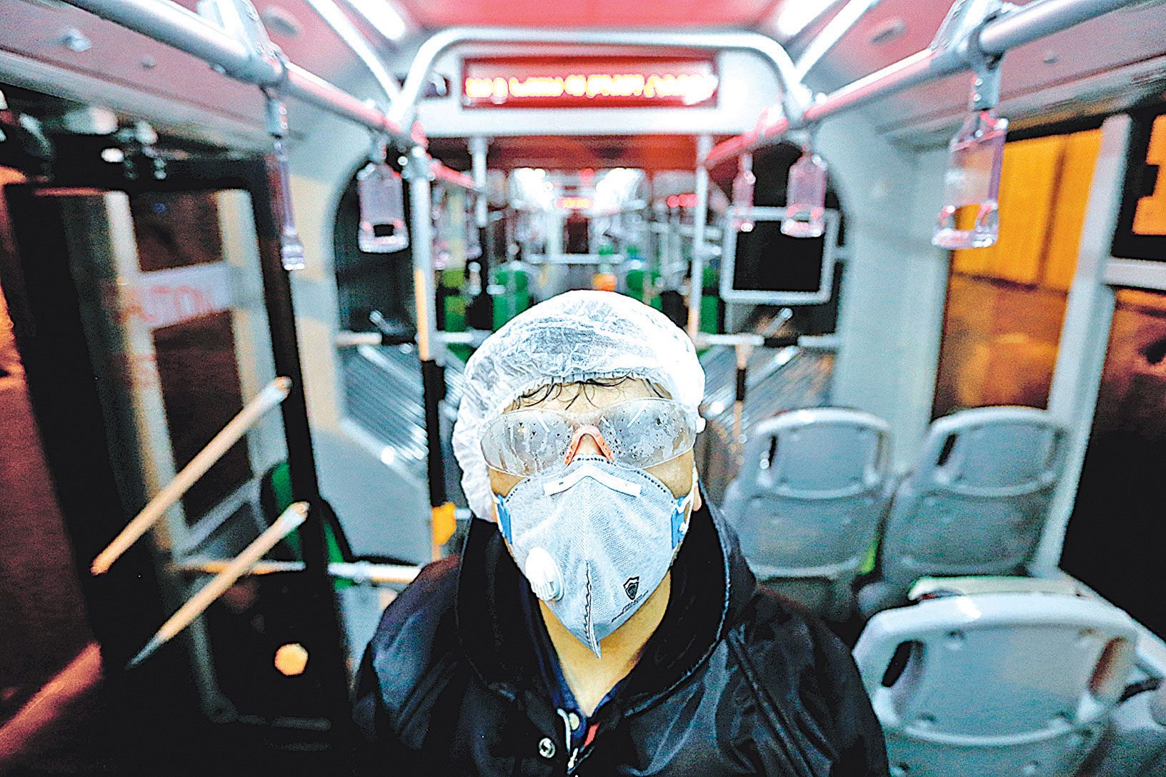 圖為2月26日德黑蘭市政府一名女員工在給巴士消毒。（Photo by ATTA KENARE / AFP）