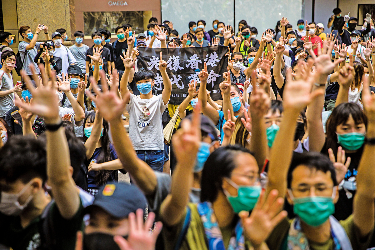 參加7.1遊行港民無懼國安法，展開「光復香港 時代革命」橫幅，做「五大訴求 缺一不可」手勢。（AFP）
