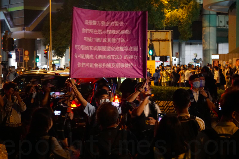 警方向悼念周梓樂的民眾舉起紫旗，警告違反「港版國安法」。（Jerry/大紀元）