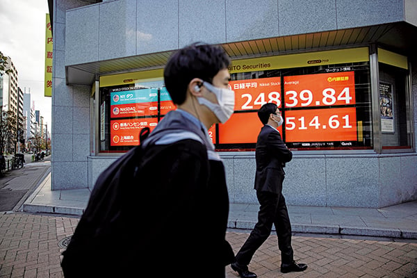 2020年11月9日，日本東京，兩名戴口罩的民眾路過電子看板。（BEHROUZ MEHRI/AFP via Getty Images）