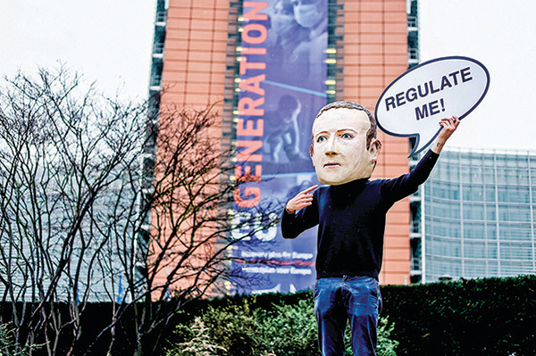 歐洲執行委員會大樓外，一名活動人士帶著印有面書行政總裁朱克伯格頭像的面具，手舉「監管我」的牌子。（Getty Images）