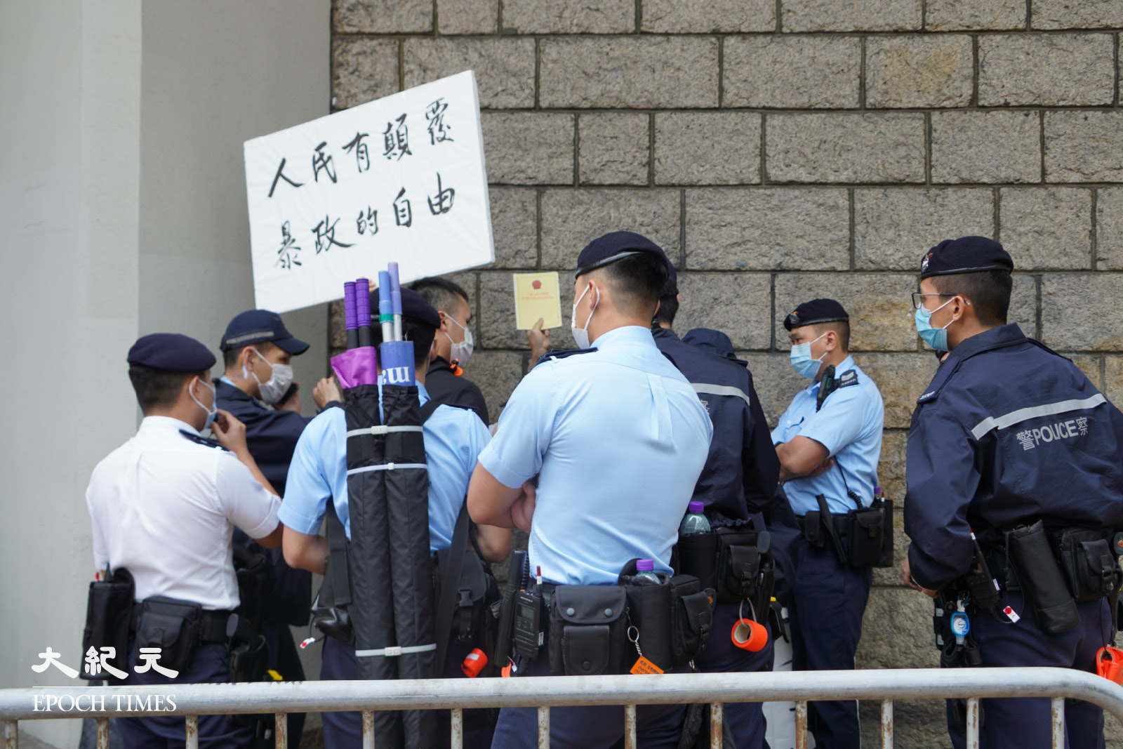 梁生被警察包圍，高舉標語牌以及《基本法》。（余鋼／大紀元）