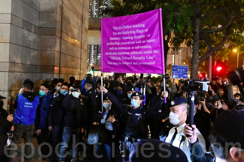 民眾3月4日晚在西九龍法院聲援民主派初選被捕者，齊唱《願榮光歸香港》，高呼「光復香港」等口號，警方舉起紫旗。（宋碧龍／大紀元）