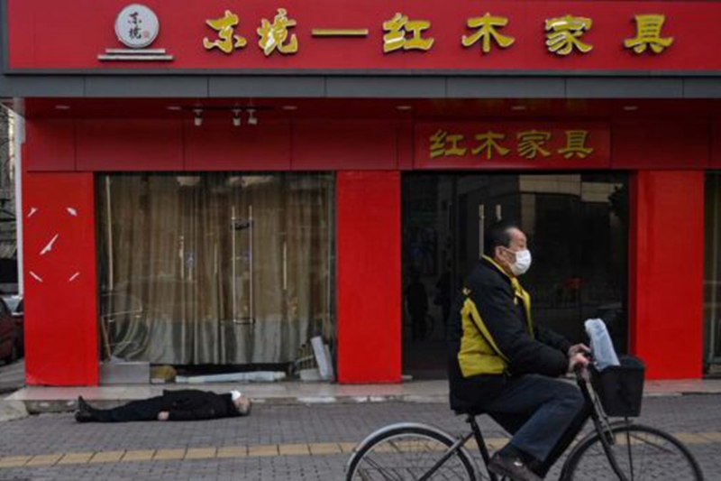 法新社刊登的照片，一名手拿購物袋的老人倒斃武漢街頭。(HECTOR RETAMAL/AFP via Getty Images)