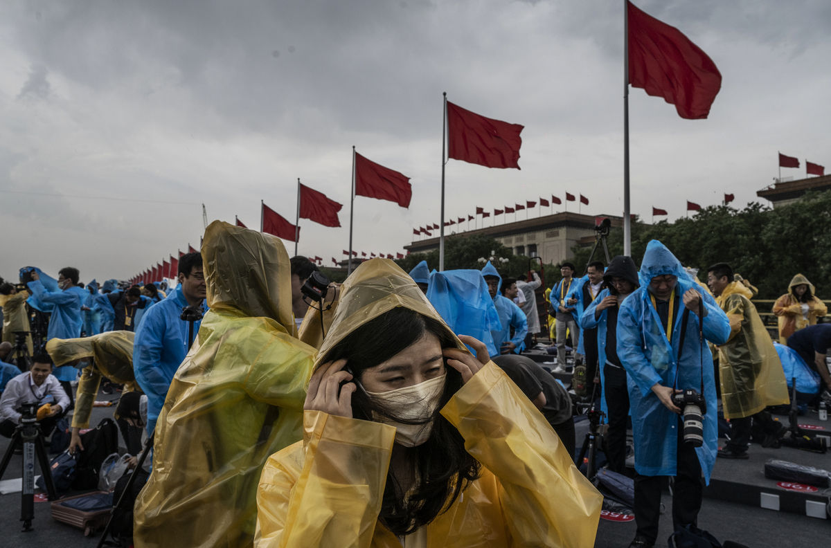 7月1日中共在天安門廣場舉行黨慶，期間下起了雨。人們趕緊穿上雨衣。（Kevin Frayer/Getty Images）