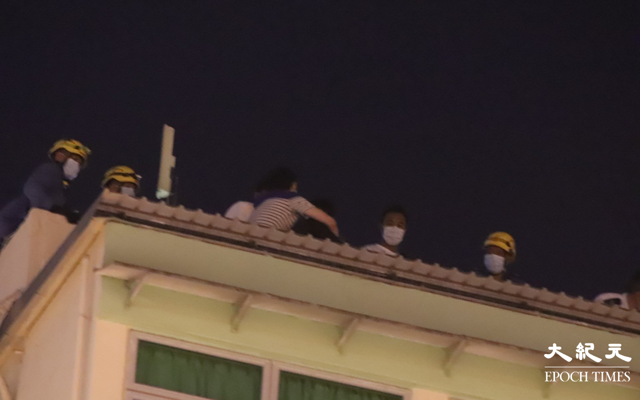 消防員於登發樓天台，向該名危坐男子進行遊說。（麥碧 / 大紀元）