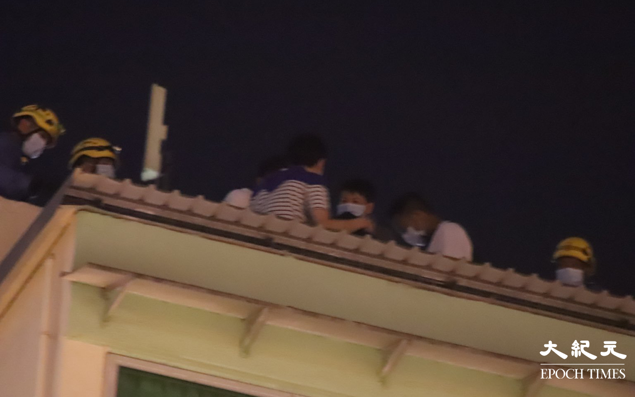 消防員於登發樓天台向該名危坐男子進行遊說。（麥碧 / 大紀元）