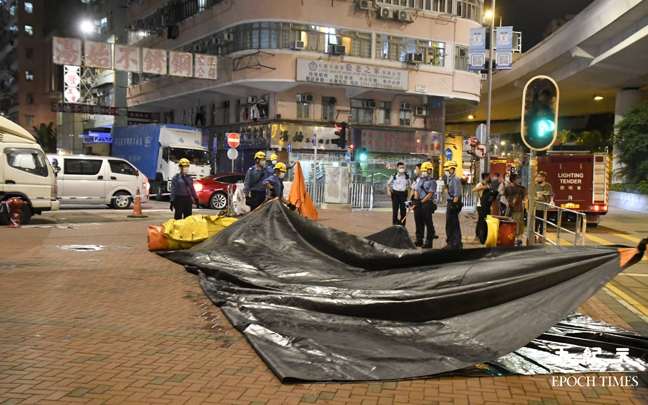晚上約9時25分，於登發樓天台危坐男子被勸回安全地方後，消防員在登發樓地面，收回救生氣墊。（麥碧 / 大紀元）