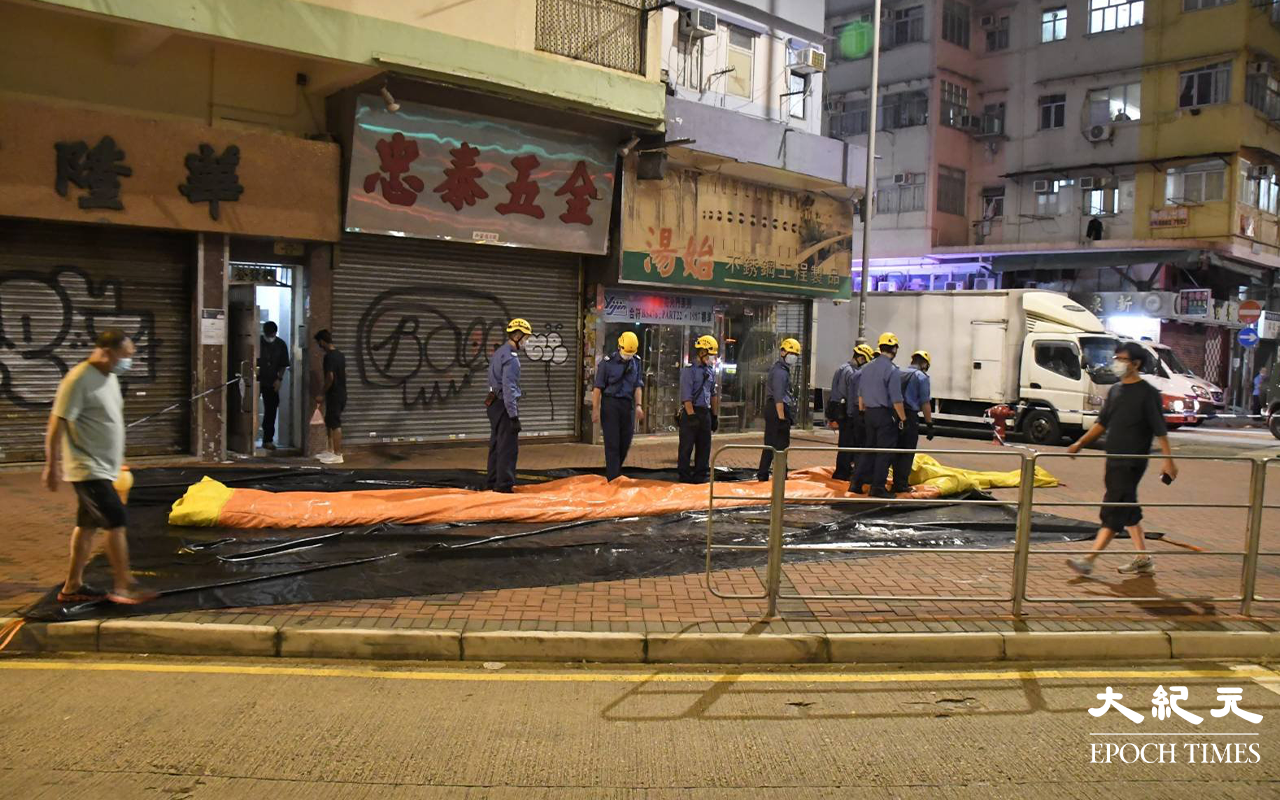 晚上大約9時25分，於登發樓天台危坐男子被勸回安全地方後，消防員在登發樓地面，收回救生氣墊。（麥碧 / 大紀元）