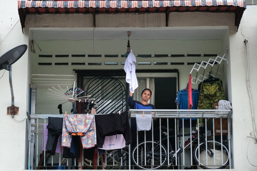 2021年7月6日，單親母親蒂爾達-卡萊瓦尼在吉隆坡的出租公寓裏，受到中共病毒大流行的影響後，揮舞著一件白襯衫作為白旗來呼救。（MOHD RASFAN/AFP via Getty Images）