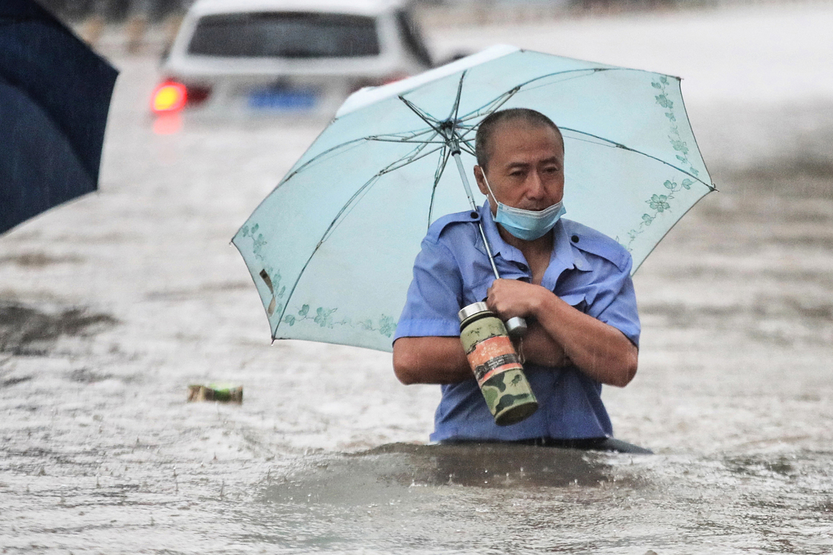 7月20日，鄭州市一名男子在暴雨後穿過街道上的洪水。（STR/AFP via Getty Images）