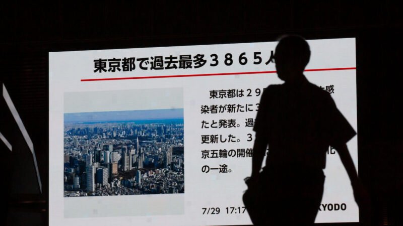 2021年7月29日，在日本東京，一名男子走過一個顯示中共病毒疾病的數字屏幕。東京都政府29日報告了3,865個新的病例，連續第三天創下歷史新高，引起東京官員的關注。（Yuichi Yamazaki/Getty Images）