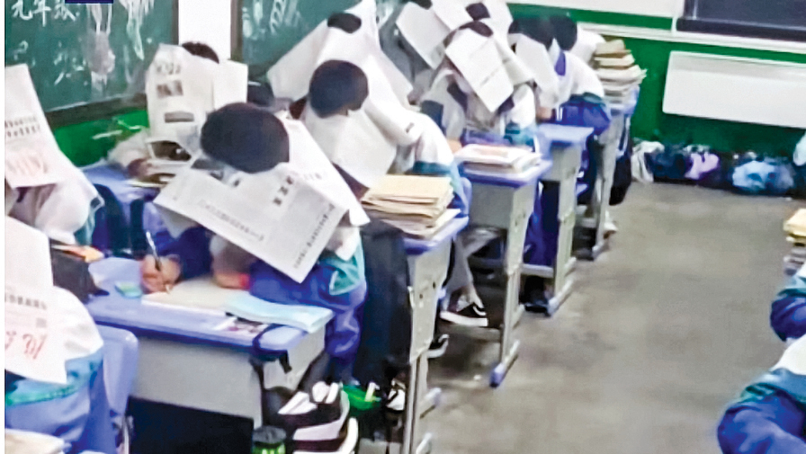 近日，甘肅慶陽一中學老師為防作弊，讓學生頭戴報紙考試。（影片截圖）