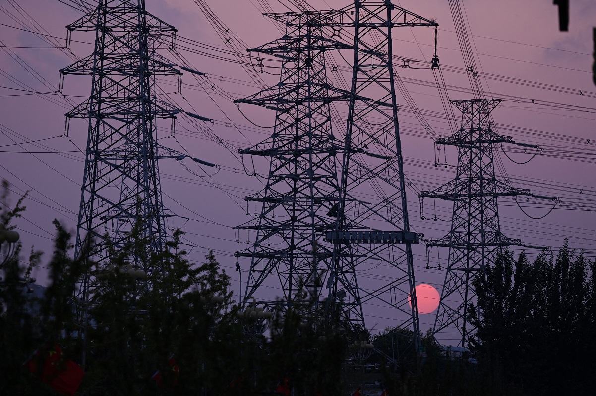 2021年9月28日，在北京，太陽從電力塔架後面落下。(LEO RAMIREZ/AFP via Getty Images)(LEO RAMIREZ/AFP via Getty Images)