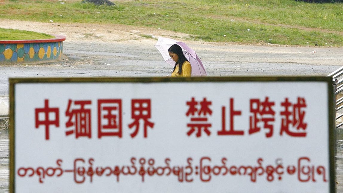 2007 年 9 月 27 日，中國雲南省中緬邊境線上，一名緬甸婦女從邊界警告牌旁邊經過。（Getty Images）