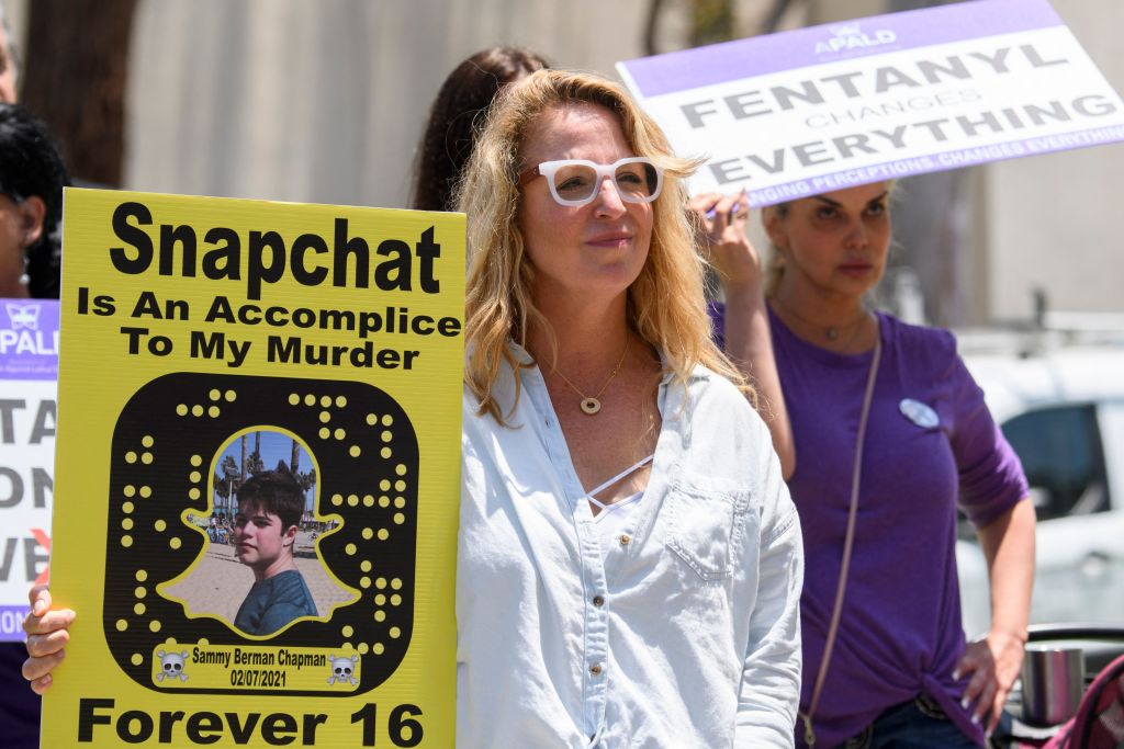 2021 年 6 月 4 日，在加利福尼亞州聖莫尼卡，人們舉著因服用含有芬太尼的藥丸中毒而死亡的親友的照片和標語，在社交媒體應用程序Snapchat 的製造商 Snap, Inc. 總部附近抗議。勞拉·伯曼博士（左），她的兒子塞繆爾在 16 歲時死於毒品，她說她的兒子就是通過 Snapchat上的某個人購買的。（PATRICK T. FALLON/AFP via Getty Images）