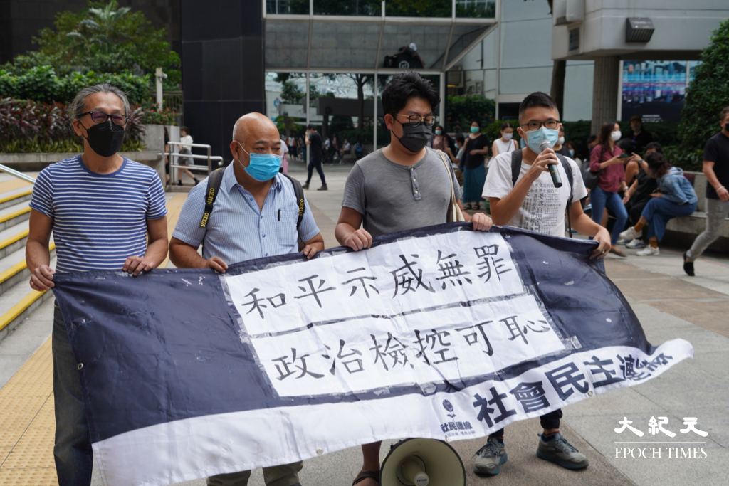 被告曾健成（左二）和鄧世禮（左一），及社民連成員今日（7日）到法庭外示威，聲援7.1遊行案被告。（余鋼／大紀元）