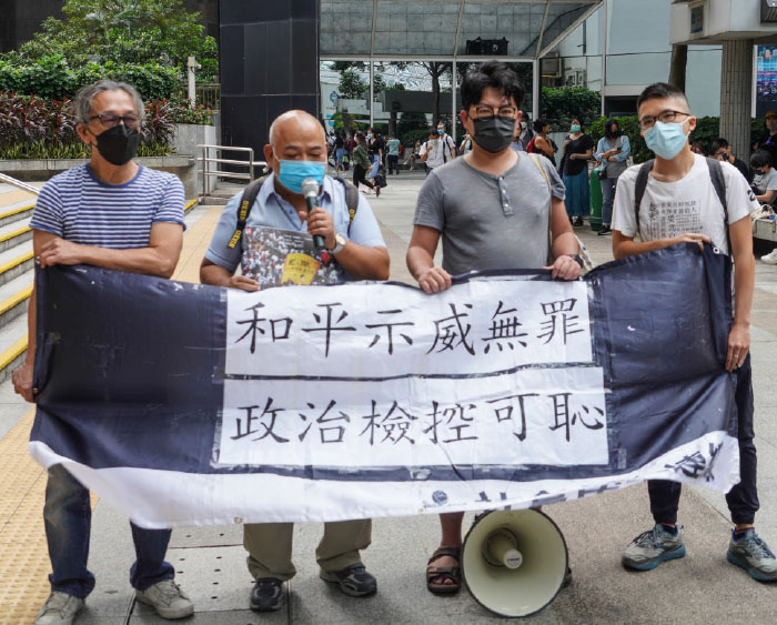 被告曾健成（左二）和鄧世禮（左一），及社民連成員昨日到法庭外示威，聲援7.1遊行案被告。（余鋼／大紀元）