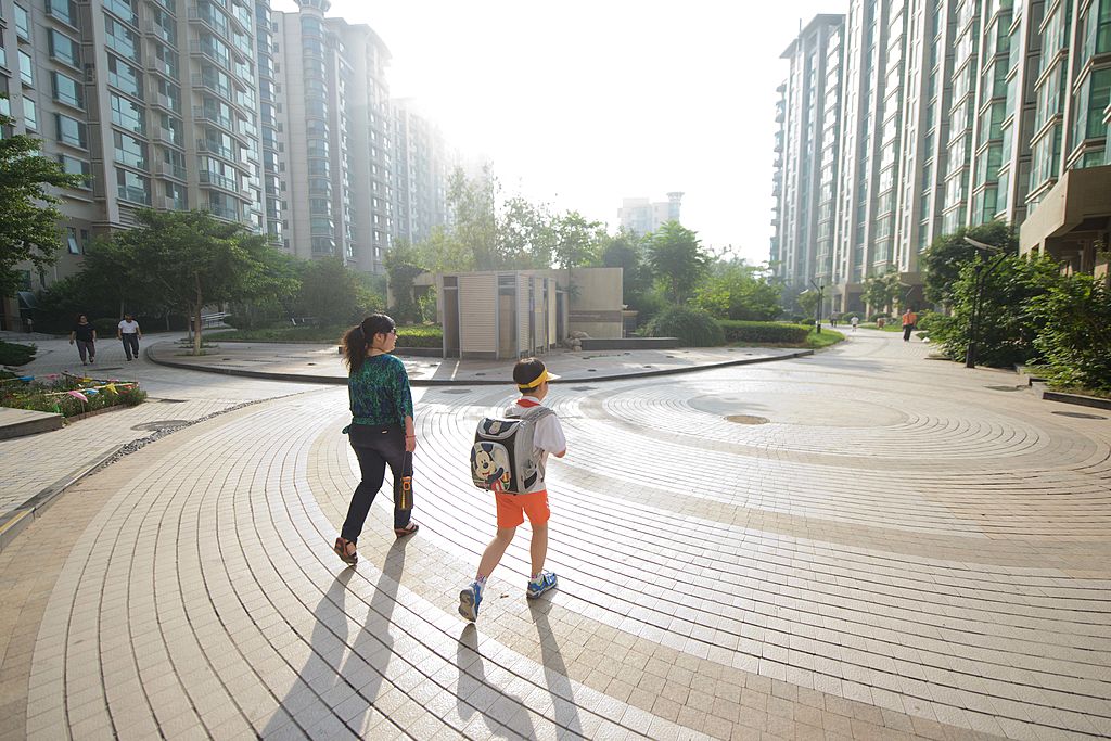 北京，一個母親帶著孩子離開居住的公寓，步行前往學校。（Ed Jones/AFP via Getty Images）