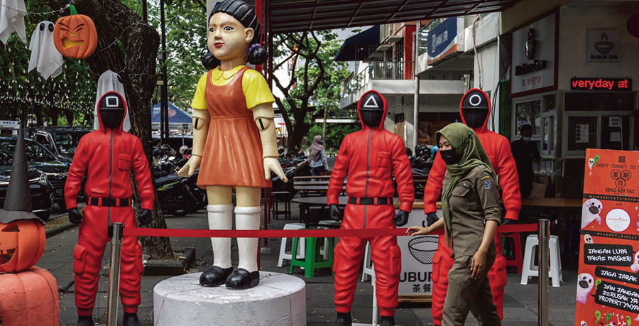 10月21日，一名婦女路過印度尼西亞東爪哇省泗水市美食廣場的《魷魚遊戲》角色雕像。（Getty Images）