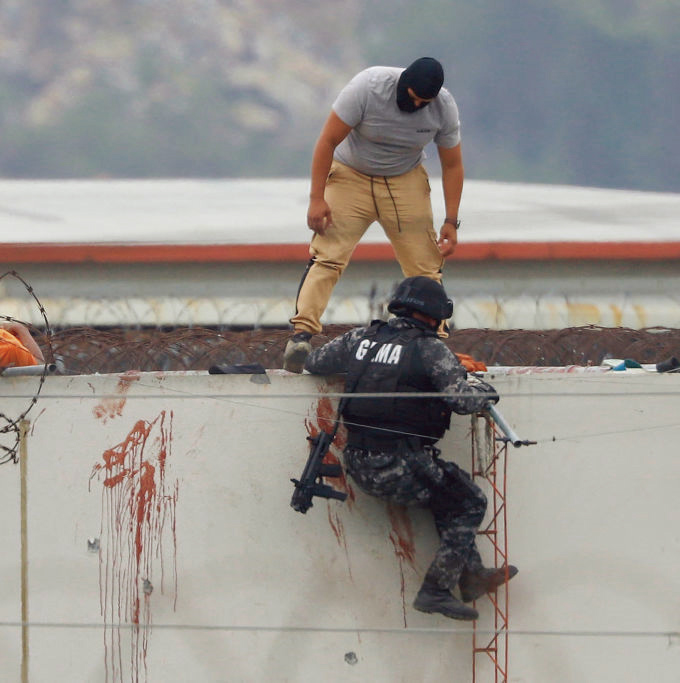 11月13日，在厄瓜多爾瓜海岸監獄屋頂上，警察準備將一具囚犯的屍體搬運下來。(Getty Images)