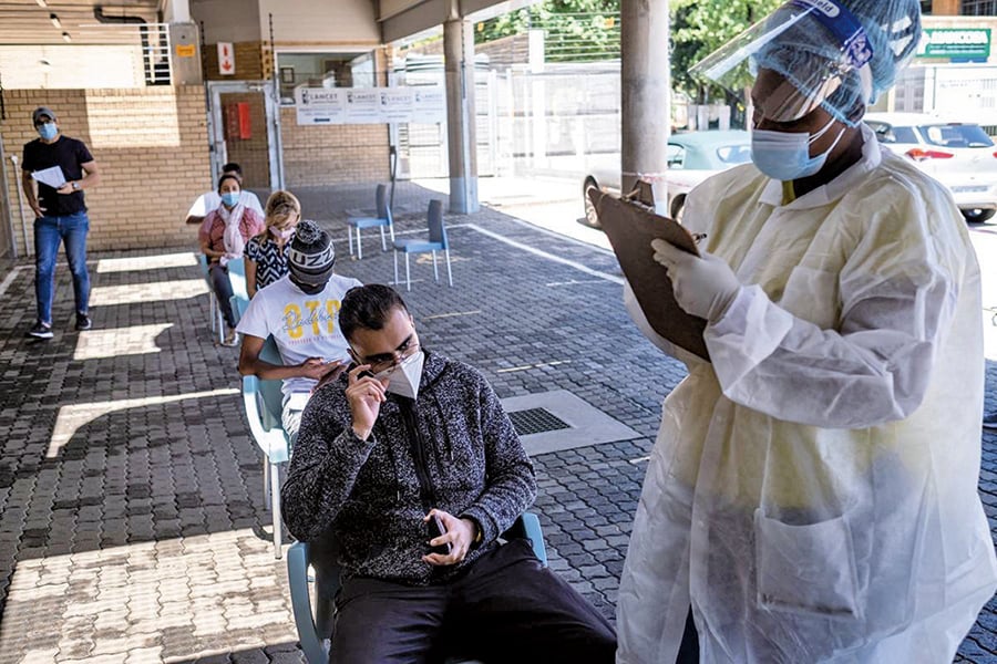11月30日，南非約翰內斯堡的一間實驗室外，一名醫護人員在進行PCR測試前，正協助患者填寫表格。（Getty Images）