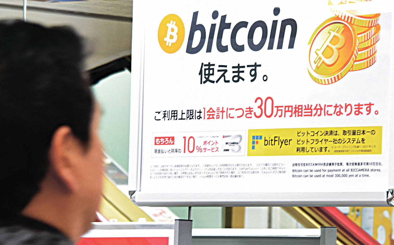 東京稅務局發現，中國資金通過比特幣等加密貨幣流入日本。圖為東京一商店可使用比特幣交易的廣告。（Toru Yamanaka/AFP）