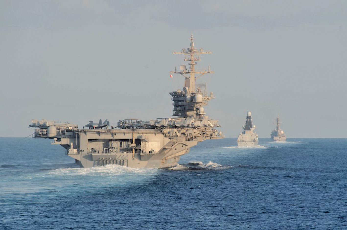 圖為2019年11月19日，美國林肯號航母（左）通過霍爾木茲海峽。（Zachary Pearson- U.S. Navy via Getty Images）