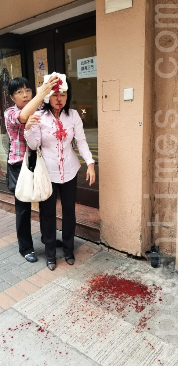 2019年9月24日，法輪功學員廖女士在長沙灣警署附近遇襲後頭部受傷，同行友人何女士試圖用毛巾幫她止血。（黃曉翔 / 大紀元）