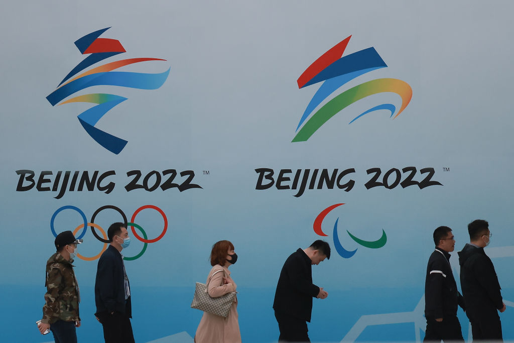 奧密克戎變種病毒業已攻入北京。2022北京冬奧會、殘奧會能否如期順利舉辦被世界聚焦。圖為北京國家游泳中心，市民戴著口罩走在北京冬奧會標誌前。（Lintao Zhang/Getty Images）