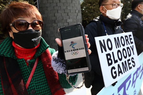 2022年2月9日，在中共駐韓國大使館前抗議的一位女士向記者展示手機上北京冬奧的標誌圖，表明抗議是針對北京冬奧。（Chung Sung-Jun/Getty Images）