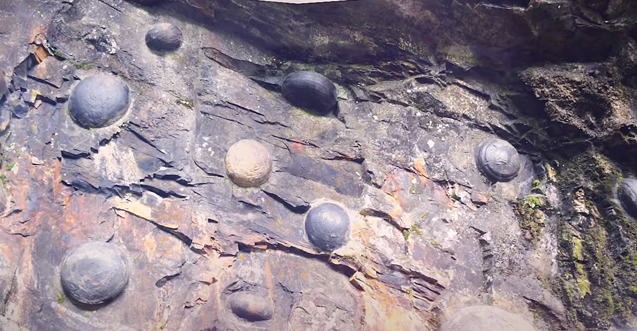 貴州三都縣有一座山崖叫產蛋崖，崖壁上嵌著大小不同蛋形的圓石頭。(未解之謎影片截圖)