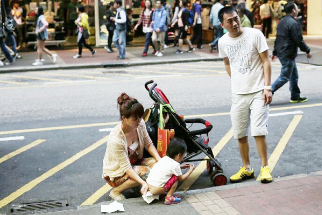 圖為2014年大陸遊客到香港旅遊，讓孩子在馬路上大小便。（網絡圖片）