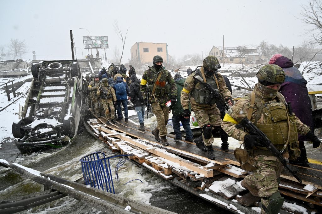 2022年3月8日，烏克蘭士兵在基輔西北部伊爾平市的平民疏散中走過一座被毀壞的橋樑。（SERGEI SUPINSKY/AFP via Getty Images）