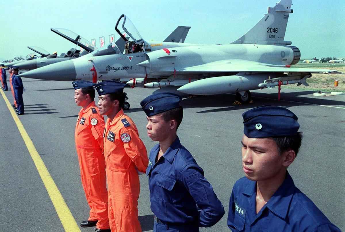 1999 年 9 月 1 日，在台灣高雄縣南部的康山，兩名飛行員和兩名技師在空軍學院慶祝軍事學院成立 70 周年飛行表演之前，與法國製造的幻象 2000-5 並列。（TAO-CHUAN YEH / AFP）