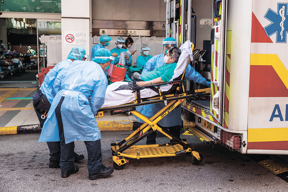 2022年3月11日，在香港瑪格麗特公主醫院急症室外，身穿個人防護裝備的醫護人員，將一名患者從救護車上卸下。（Dale de la Rey/AFP via Getty Images）