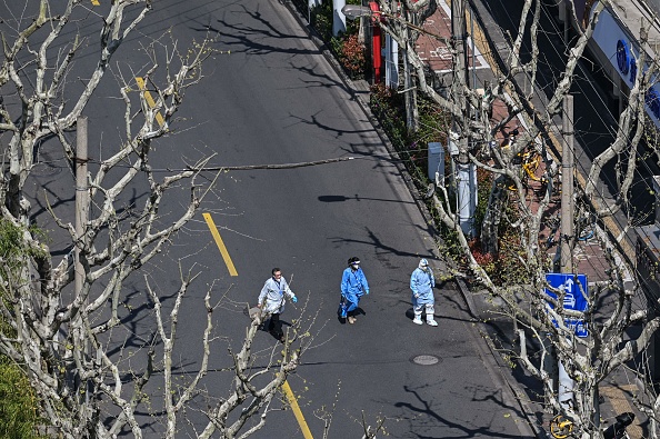 上海封城後，越來越多的問題令民怨沸騰。圖為2022年4月3日，上海靜安區街道上，3名防疫人員在行走。（HECTOR RETAMAL/AFP via Getty Images）