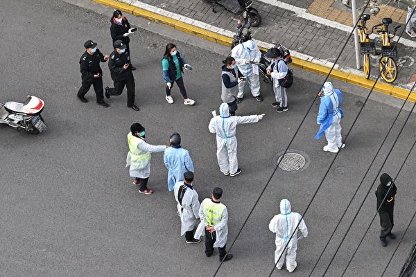 2022年4月1日，在上海靜安區COVID-19封鎖的第二階段，穿著個人防護裝備的人向街上的居民打手勢。（HECTOR RETAMAL/AFP via Getty Images）