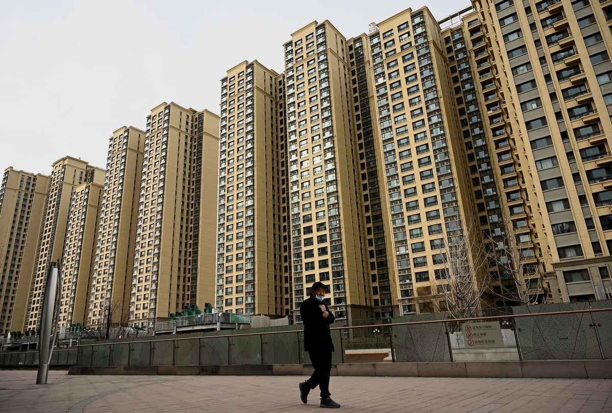《2022.CF40中國金融改革報告》提出「構建面向新市民的都市圈建設方案」，讓農民工在郊區集中建房居住。圖為2021年12月8日，一名男子走過中國房地產開發商恒大在北京的住宅區。（Noel Celis / AFP）