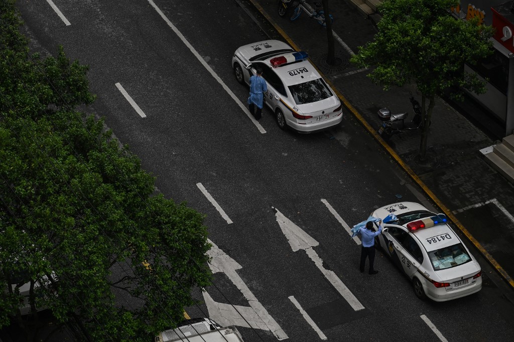 圖為2022年4月26日，上海靜安區，在疫情封鎖期間街道上的警察和警車。（Hector RETAMAL / AFP）