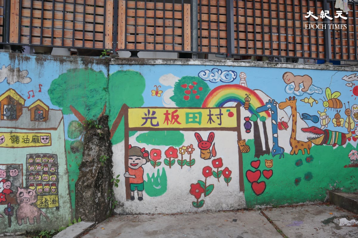 在光板田村內的一面大牆壁 ，繪畫了各式各樣的動植物，藍天白雲配上彩虹，充滿著愉快的感覺。（樂樂／大紀元）