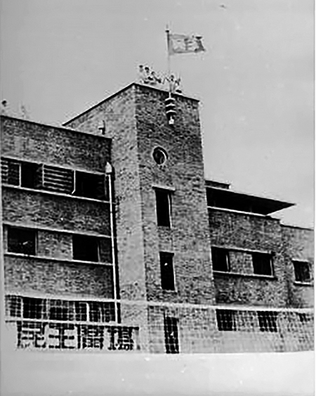 1947年6月1日，北大學生在民主廣場北端灰樓頂上升起民主旗（綠底白字，上有「民主」二字）。（公有領域）